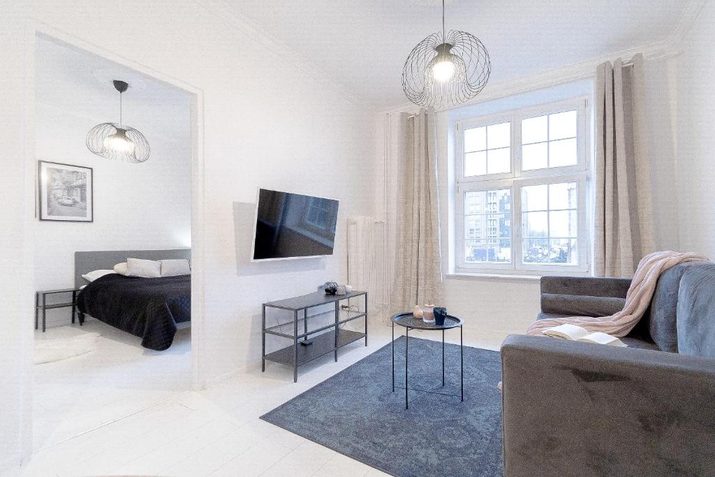 a white living room with a bed and a television at Glow Apartments, Apartamenty Śródmieście in Gdańsk