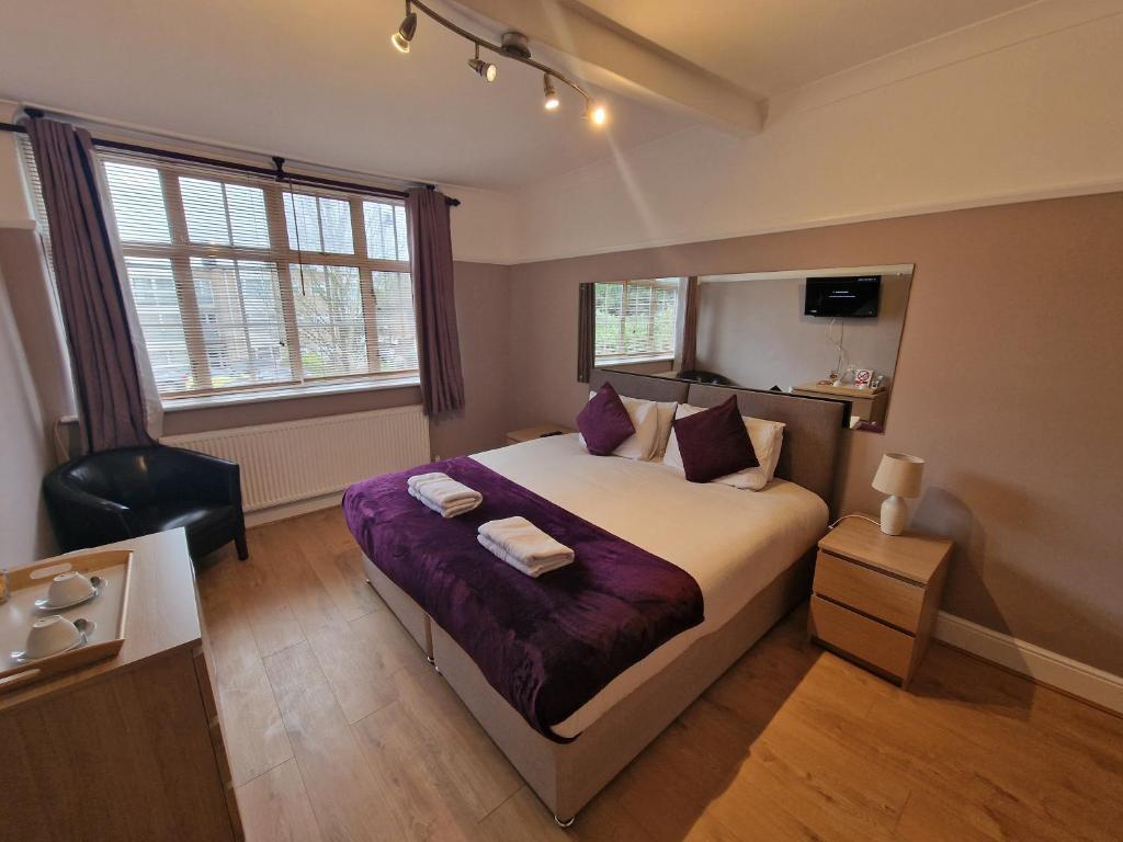 a bedroom with a large bed with purple sheets at Kathleen House in Enfield