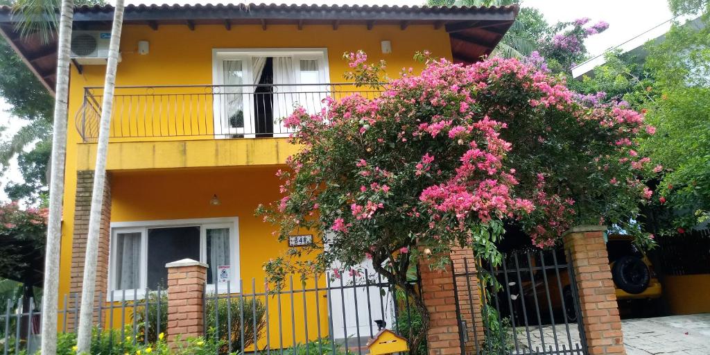 a yellow house with pink flowers in front of it at Quarto na Praia de Taquaras in Balneário Camboriú