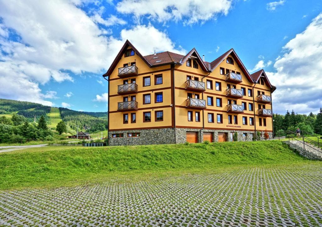 a large building on top of a green hill at Apartmány Telgárt in Telgárt