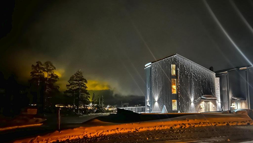 un edificio alto con luces encendidas por la noche en Trilodge - Unique cabin with high standard, views, ski in & out, attractive location, en Meråker
