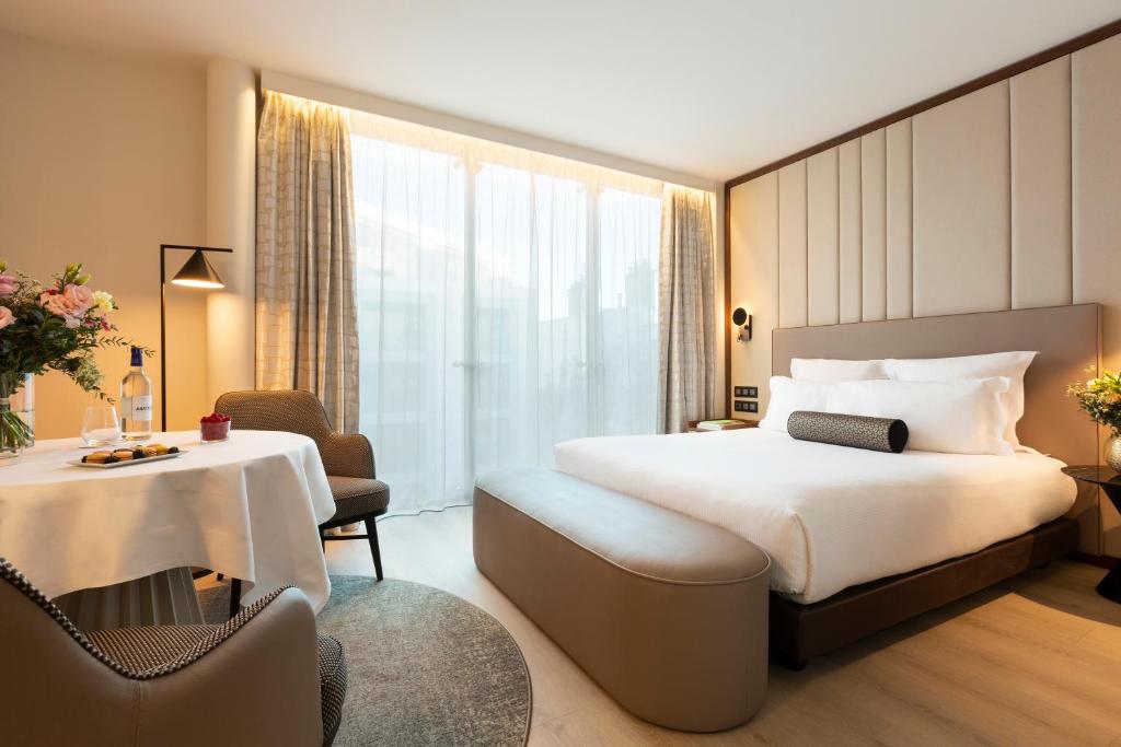 um quarto de hotel com uma cama grande e uma mesa em La Clef Tour Eiffel Paris by The Crest Collection em Paris