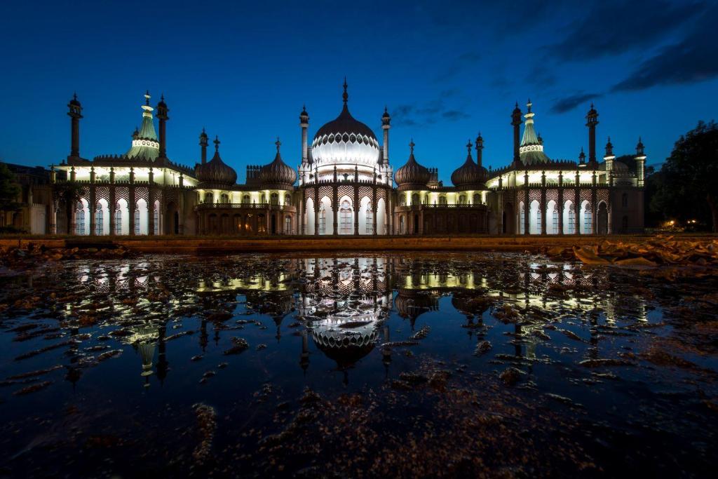 a large building with a reflection in the water at night at Maldron Hotel Brighton City Centre in Brighton & Hove
