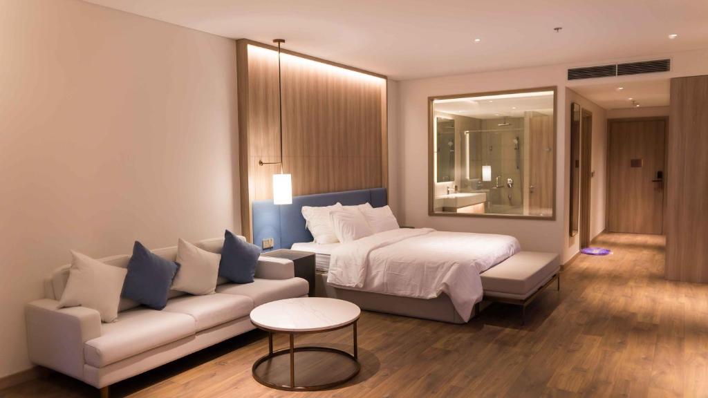 a hotel room with a bed and a couch at Anstay Residence by A La Carte Hạ Long in Ha Long