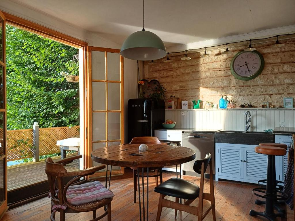 une cuisine avec une table, des chaises et une horloge murale dans l'établissement The Riverview Loft, à Sainte-Foy-la-Grande