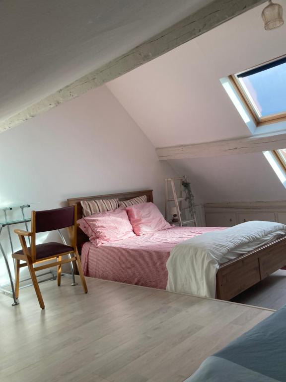 een slaapkamer met 2 bedden, een stoel en een raam bij Chambre avec 4 couchages plein cœur de village in Neauphle-le-Château