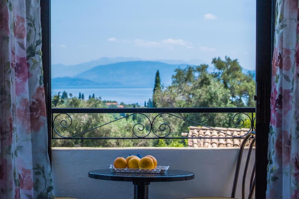 a table with three oranges on a balcony with a view at Aggeliki apartments Dassia By Hotelius in Kato Korakiana