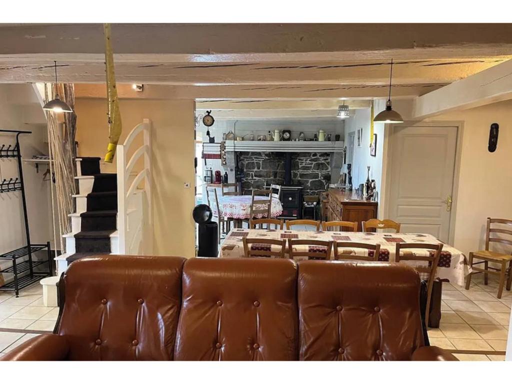 una sala da pranzo con tavolo e sedie in pelle marrone di Maison de Famille de 1823 a Chastreix