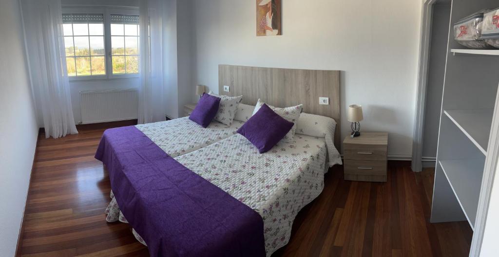 a bedroom with a bed with purple blankets and pillows at Viviendas vacacionales as lagas in Palas de Rei