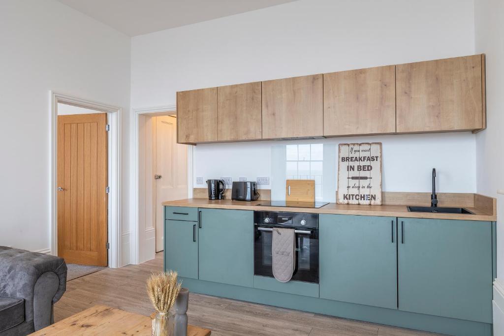 una cucina con armadi blu in soggiorno di Seaside Bliss - Seafront Apartments a Kent
