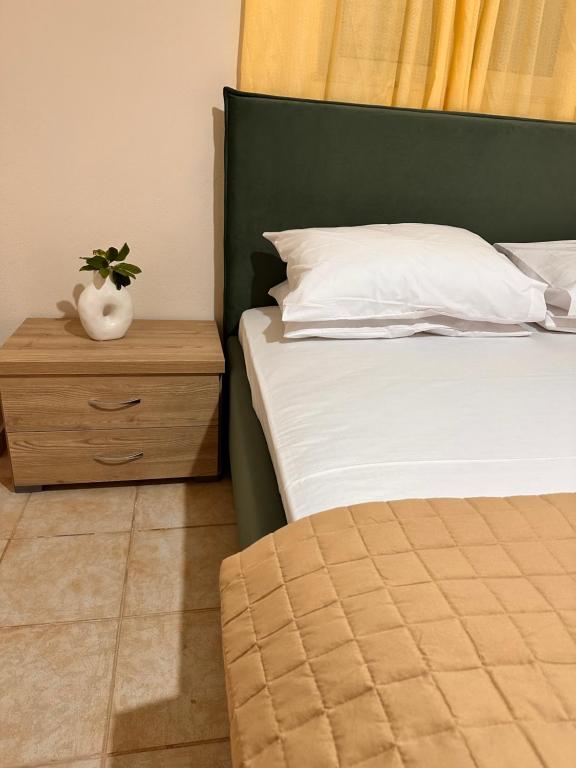 ein Bett mit einem grünen Kopfteil und einem Nachttisch mit einer Pflanze darauf in der Unterkunft Luxury Beach House 2 in Xiropigado