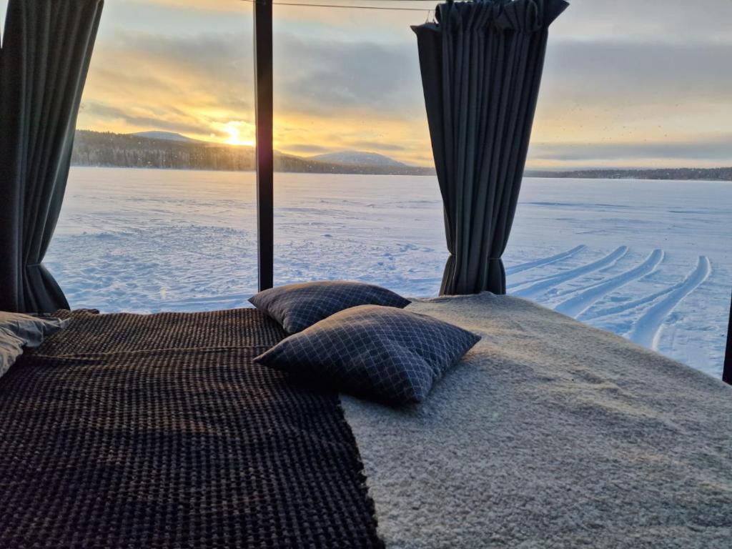 a bed in a room with a view of the snow at Aurora Hut Salla in Tikkala