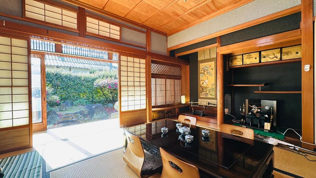 een kamer met een bureau en een groot raam bij Guest House 古民家 NAGOMI in Izumi-Sano