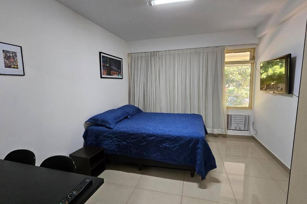 a bedroom with a blue bed and a window at Conforto e Localização Perfeita in Brasília