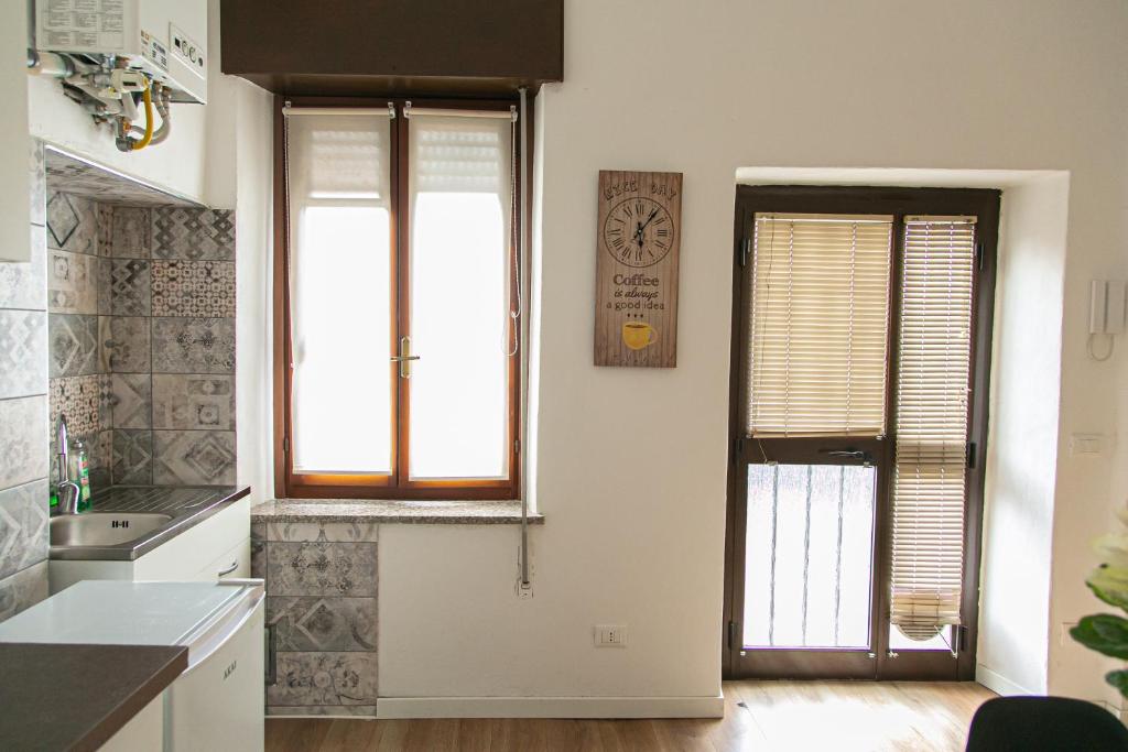 una cucina con due finestre, un lavandino e un orologio di Alla Fiera apartment a Bergamo