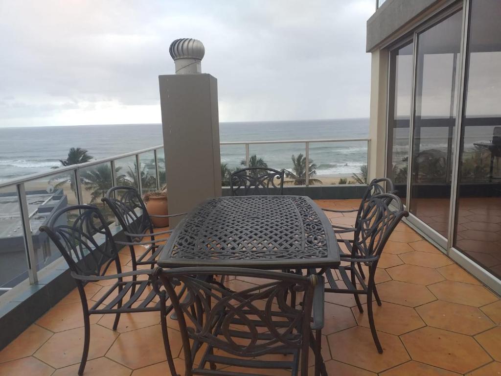 a table and chairs on a balcony with the ocean at Rondevoux 27 in Margate