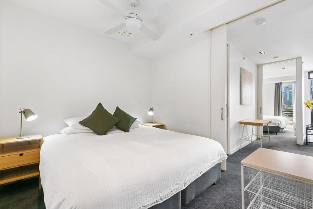 a white bedroom with a large bed and a table at East Melb 2bed parking pet friendly in Melbourne