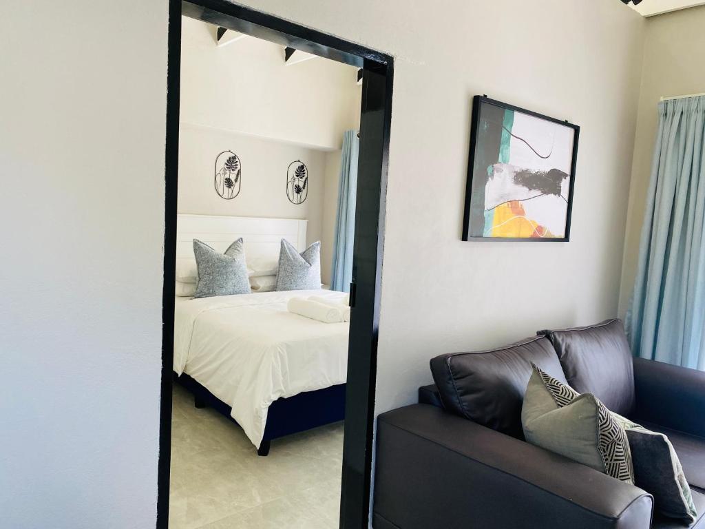 a mirror in a bedroom with a bed and a couch at Cozy Garden Facing Guest Suite -(Back up power) in Midrand