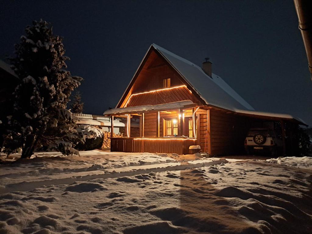 una cabaña de madera en la nieve por la noche en Chalupa u Urbanov, en ľubeľa