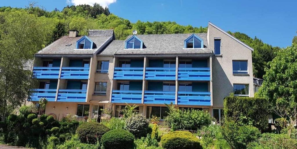 een uitzicht op een groot huis met blauwe balkons bij Le Castel du Cantal Groupe Village Fani in Thiézac