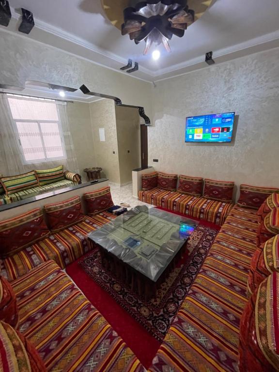 a room with couches and a table and a tv at Dar Kernaf Eco House For Families I Entire Comfy Appartment I Fibre Internet Up to 100 Mbps I PALMS in Er Rachidia