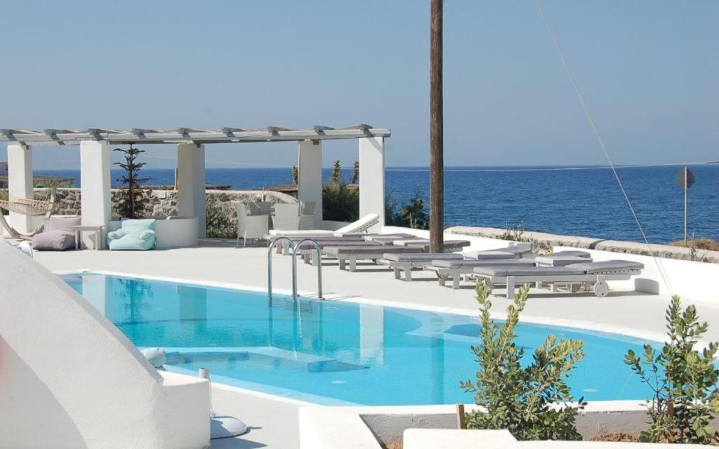 basen z leżakami i ocean w tle w obiekcie Sea paradise villas - Seaside & private jacuzzi w mieście Oia