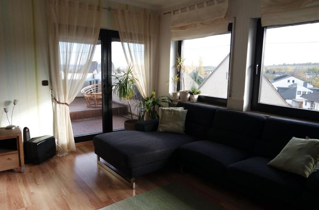uma sala de estar com um sofá e janelas grandes em Ferienwohnung Rübenach em Koblenz