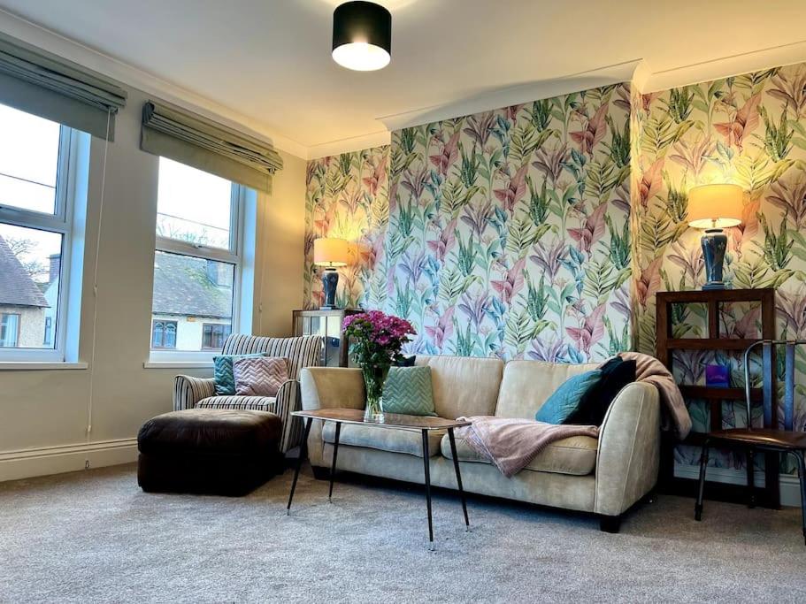 een woonkamer met een bank en bloemenbehang bij The Lily•Central Beeston•Private Apartment•SmartTV•Free Wi-Fi•Tram• in Nottingham