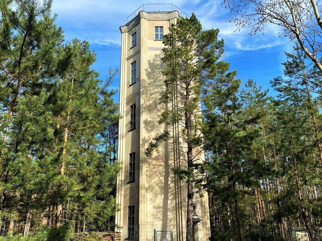 ein hohes Gebäude mit Bäumen davor in der Unterkunft Wasserturm Spreewitz in Spreewitz