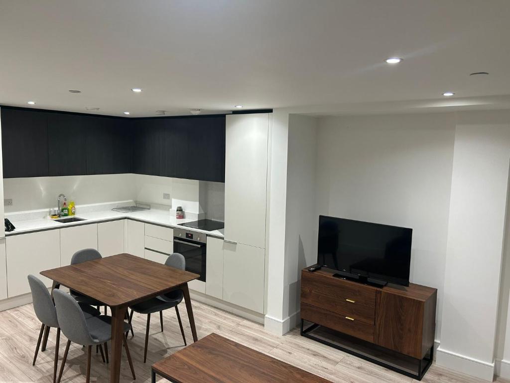 a kitchen with a table and a television and a table and chairs at Spacious 2 Bed Ilford London in Ilford