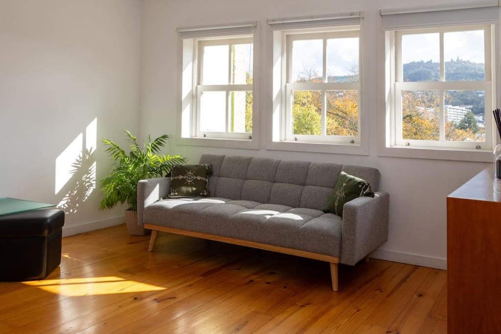 ein Sofa im Wohnzimmer mit Fenstern in der Unterkunft Moniz Terrace in Guimarães