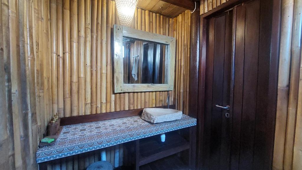 ein Badezimmer mit einem Waschbecken, einem Spiegel und einer Holzwand in der Unterkunft Meno Island Villas in Gili Meno