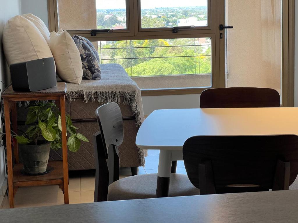 ein Wohnzimmer mit einem Tisch, einem Sofa und einem Fenster in der Unterkunft Dpto 11-UNNE in Resistencia