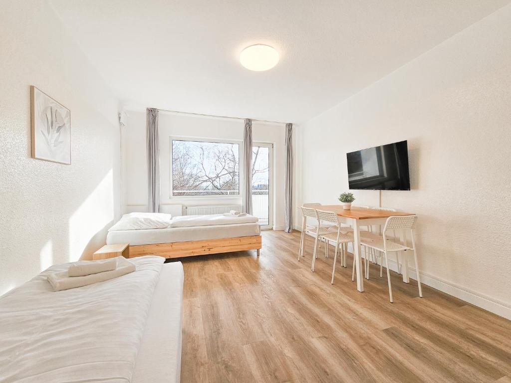 ein Zimmer mit zwei Betten und einem Tisch und einem Fernseher in der Unterkunft Tolstov Apartments - Monteurwohnungen - 2 Schlafzimmer - Küche - Balkon - Waschmaschine - 25 Min zur Messe DUS in Heiligenhaus