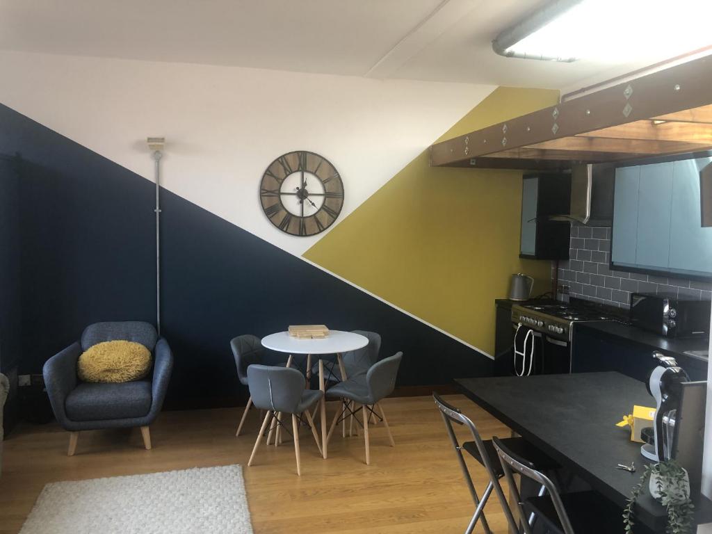 a kitchen with a table and chairs and a clock at Toothbrush Apartments - Central Ipswich - Lloyds Avenue in Ipswich