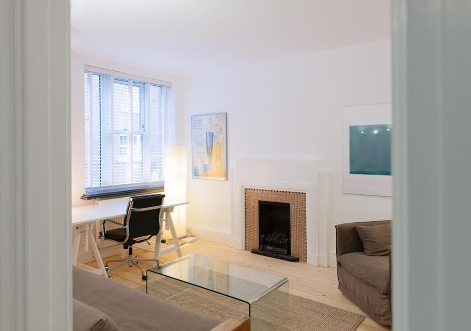 a living room with a desk and a fireplace at Bright wood-floor apartment near Parliament in London