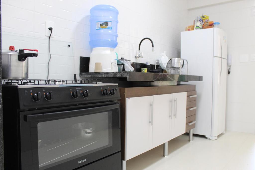 eine Küche mit einem schwarzen Herd und einem Kühlschrank in der Unterkunft Apt novissimo 3 quartos c elevador a 300m da orla Praia do Morro in Guarapari