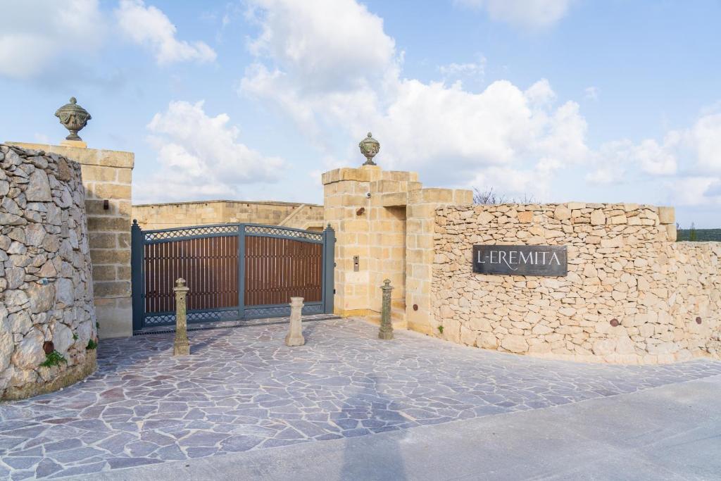 a building with a gate and a stone wall at L-Eremita Boutique Hotel in Qala