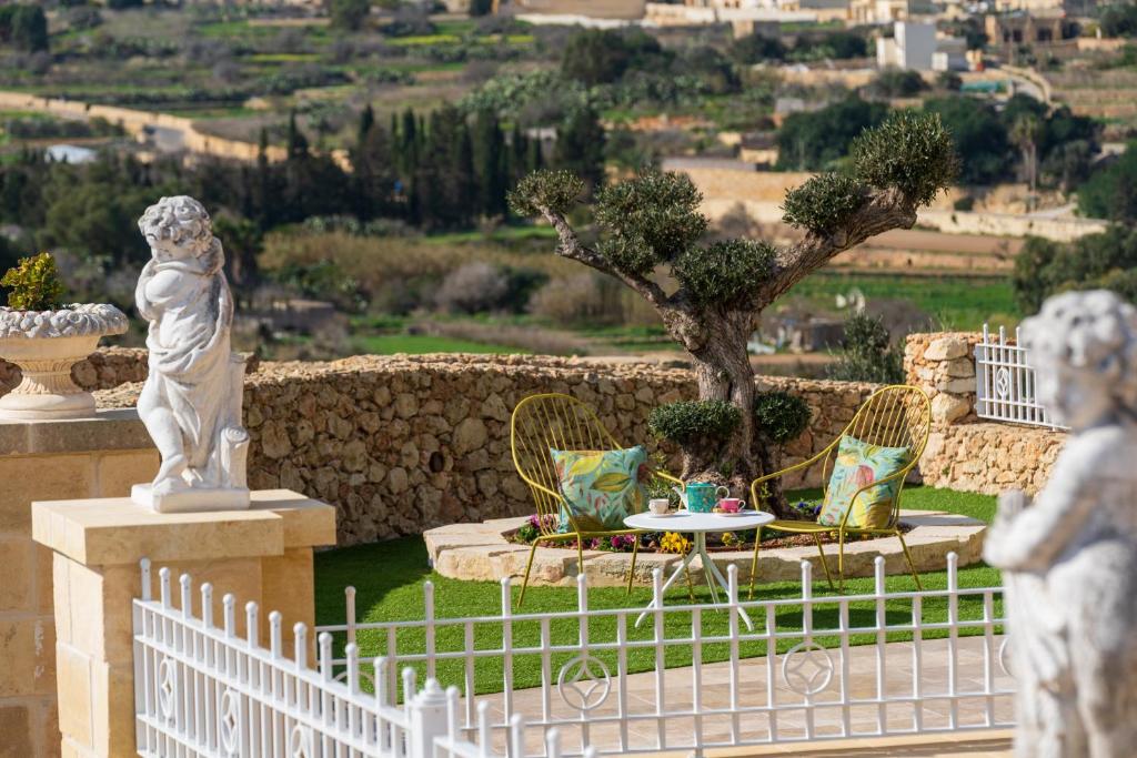 a white fence with a statue and a table at L-Eremita Boutique Hotel in Qala