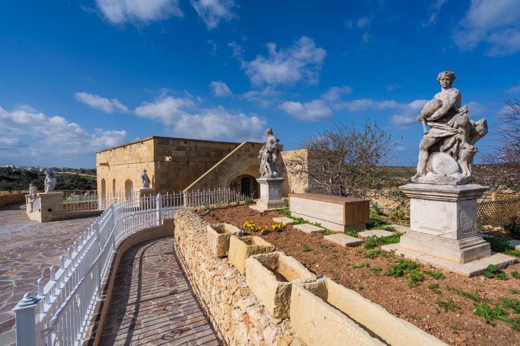 a statue and a fence in front of a building at L-Eremita Boutique Hotel in Qala