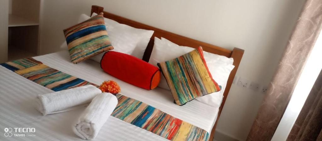 ein Bett mit bunten Kissen und Handtüchern darauf in der Unterkunft UNIPLEX HOMES in Mombasa