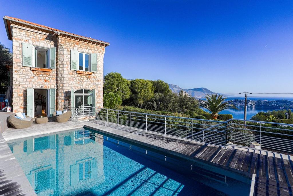 a villa with a swimming pool in front of a house at Villa de charme moderne avec piscine et vue mer in Nice