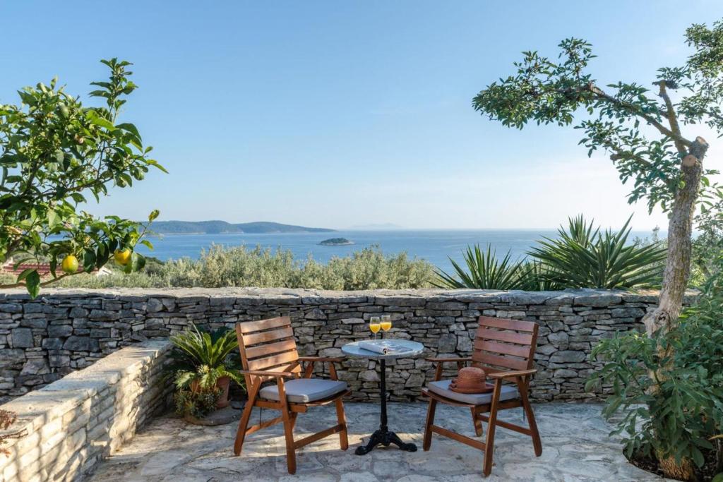 ein Tisch und zwei Stühle neben einer Steinmauer in der Unterkunft Sea View House Sanja With Terrace - Happy Rentals in Vela Luka