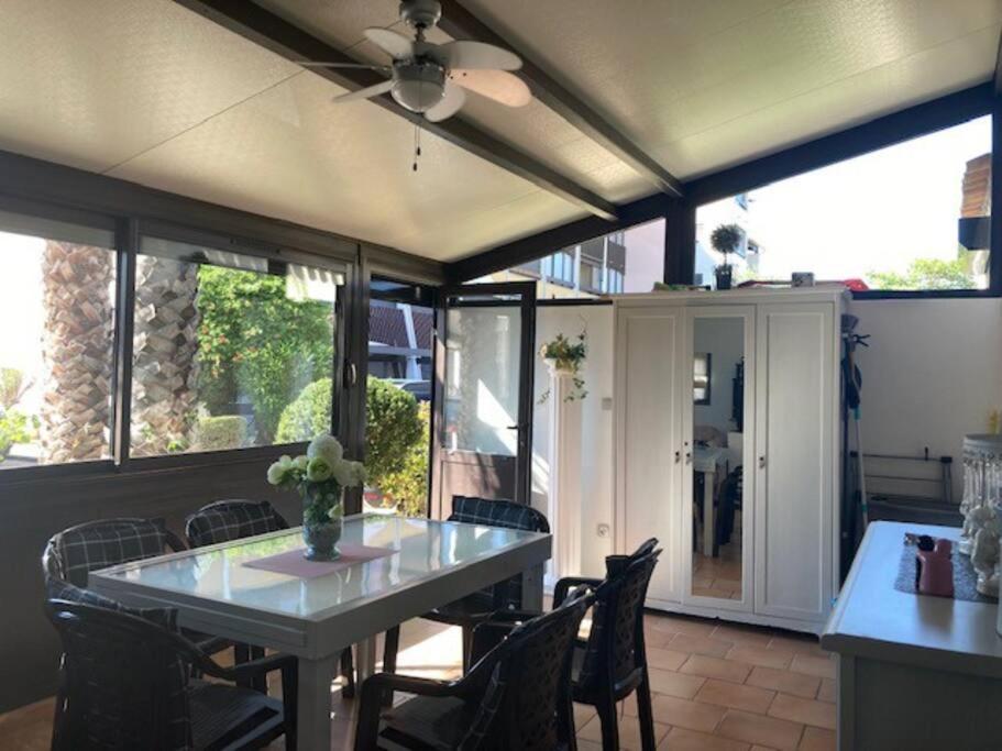 une salle à manger avec une table, des chaises et des fenêtres dans l'établissement Villa 53, Port Vénus au village naturiste, au Cap d'Agde