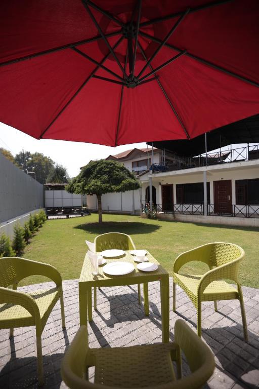 a table and chairs under a red umbrella at Lake Resort The Island Hotel in Srinagar