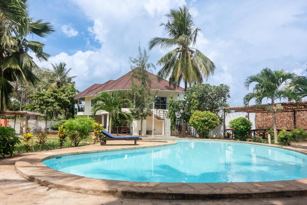 a swimming pool in front of a house with palm trees at Villa Black Pearl - new private Villa in Diani Beach