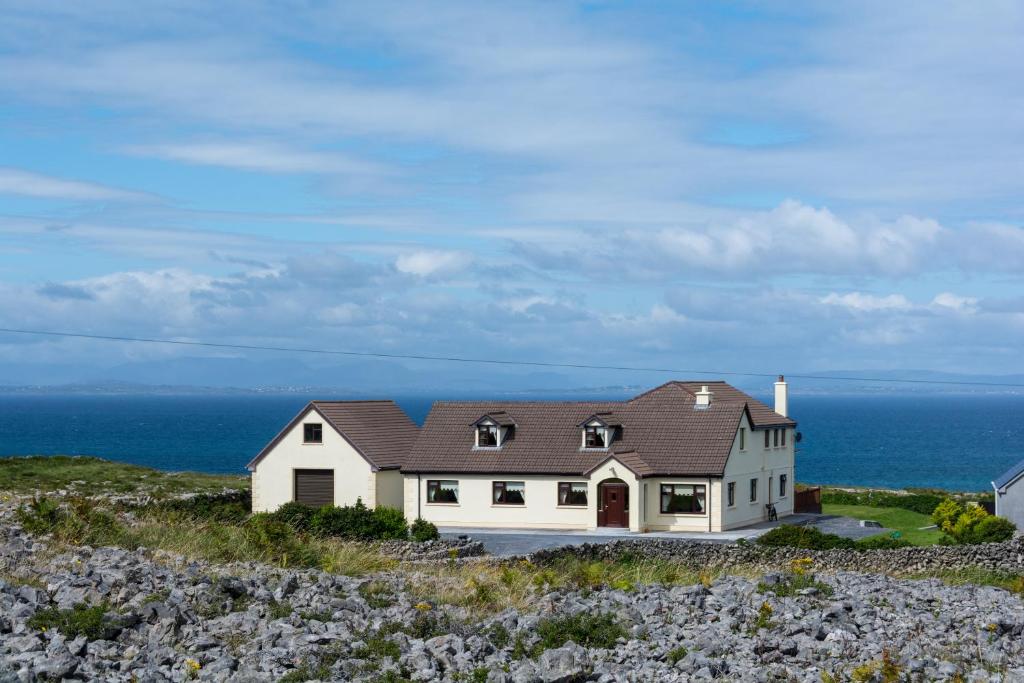 une maison sur une colline avec l'océan en arrière-plan dans l'établissement Port Aran House, à Kilronan