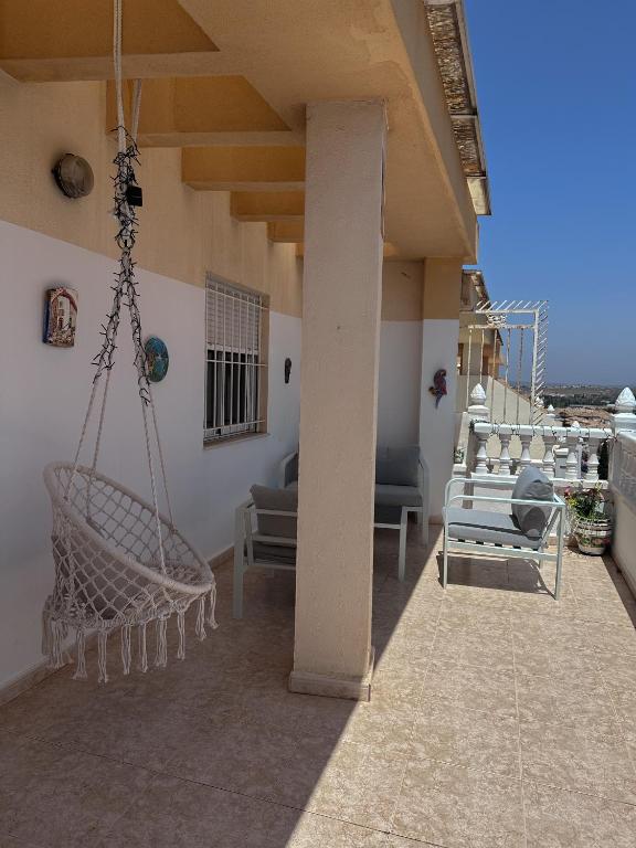 a porch with a swing and chairs on a balcony at Casa Gintare Torrevieja Beach in Torrevieja