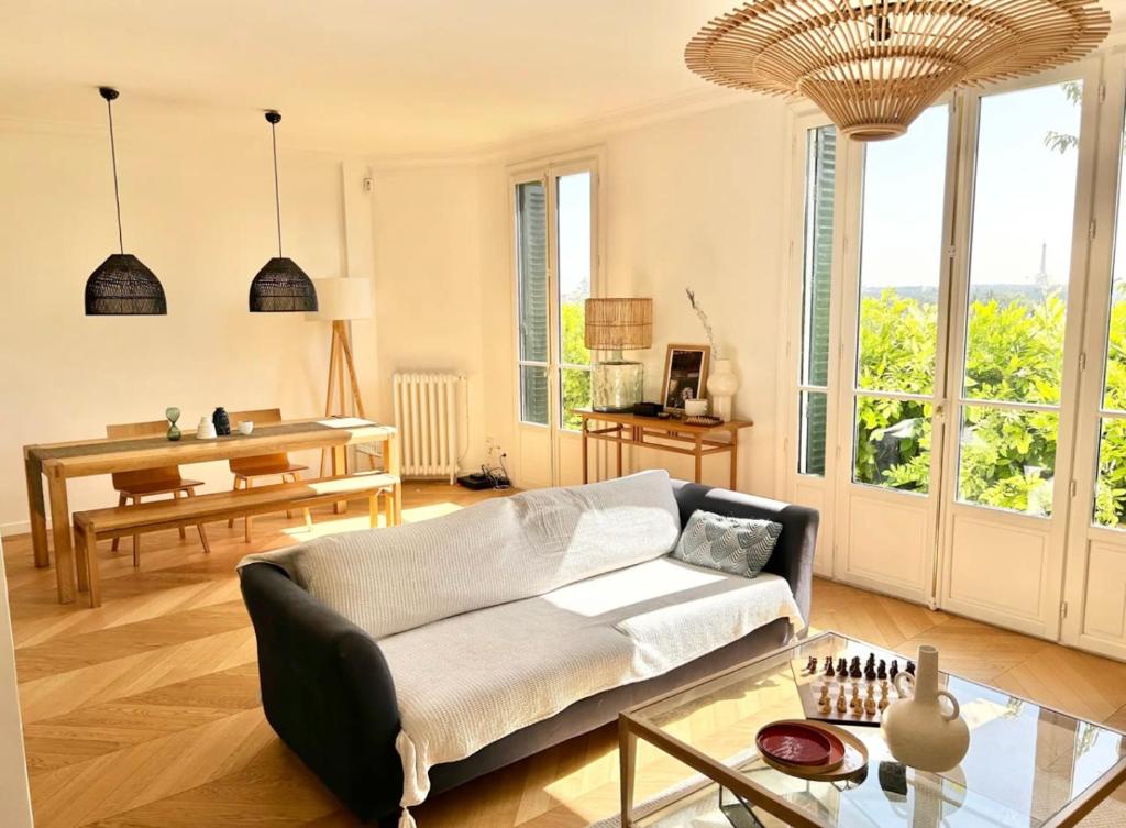 een woonkamer met een bank en een tafel bij Maison familiale avec vue Tour Eiffel in Suresnes