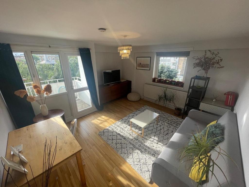 a living room with a couch and a table at Queens Park Vibrant 1BR Flat with Balcony in London